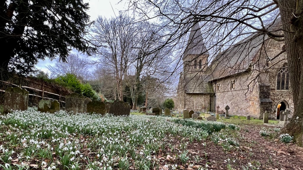 St Nicholas Church with view over churchyard and snowdrops blooming.
