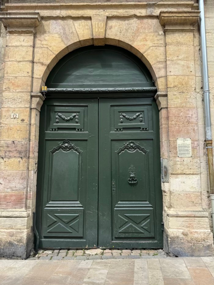dark green double doors on a sandstone building, arch top