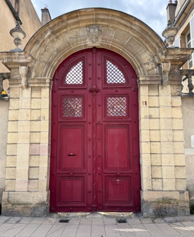 a burgundy colour double door set into a sandstone archway.