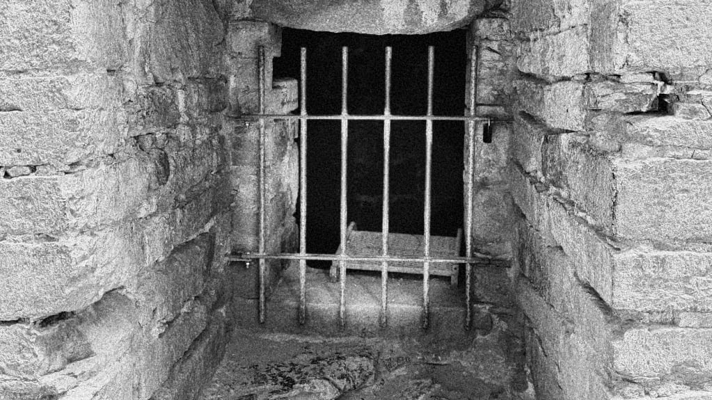 photo taken at Hammerhus on Bornholm B&W, iron bars, stone door frame, darkness inside cell as there are no windows.