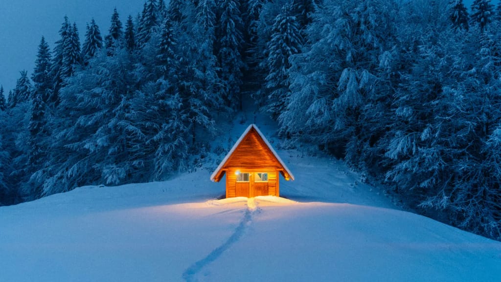 cabin in the forest surrounded by snow