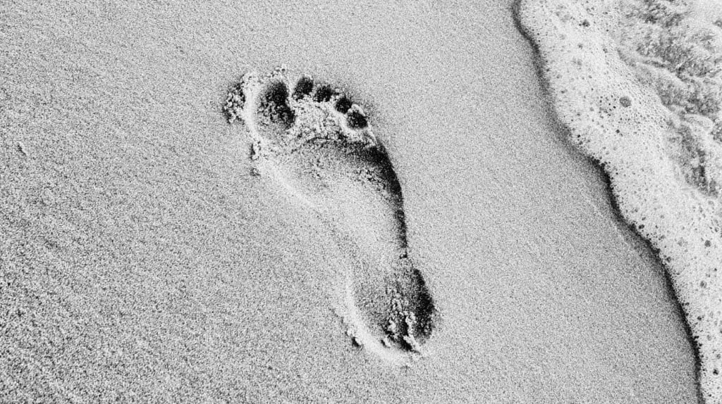 B&W image bare foot imprint on a sandy beach